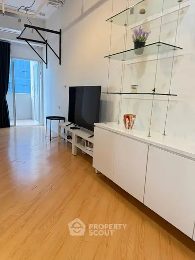 Modern living room with sleek TV stand and glass shelves, featuring a balcony view.