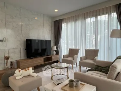 Elegant living room with modern decor, large TV, and plush seating, perfect for relaxation and entertainment.