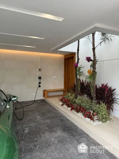 Modern home entrance with electric car charging station and lush garden