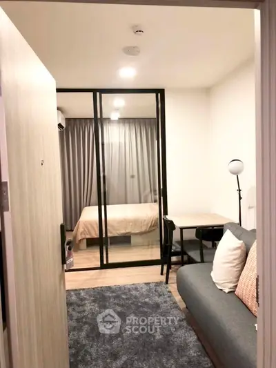 Modern apartment interior with cozy living room and glass partitioned bedroom, featuring stylish decor and lighting.