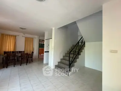 Spacious open-plan living area with dining set and staircase, perfect for family gatherings.
