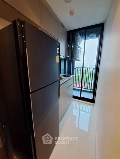 Modern kitchen with sleek appliances and balcony view in a stylish apartment.