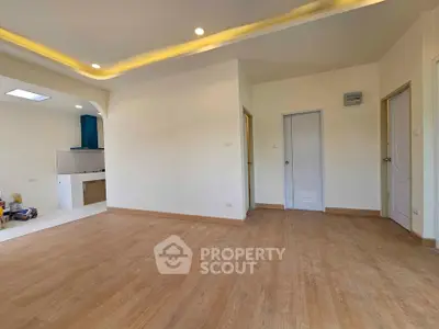 Spacious empty room with wooden flooring and modern lighting