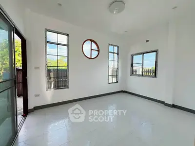 Bright empty room with large windows and unique circular window design.