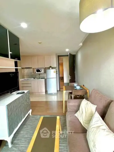 Modern living room with open kitchen, stylish furniture, and natural light in a cozy apartment.