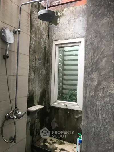 Rustic outdoor shower with natural stone walls and window view
