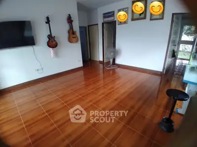 Spacious living room with wooden flooring and wall-mounted TV, perfect for entertainment.