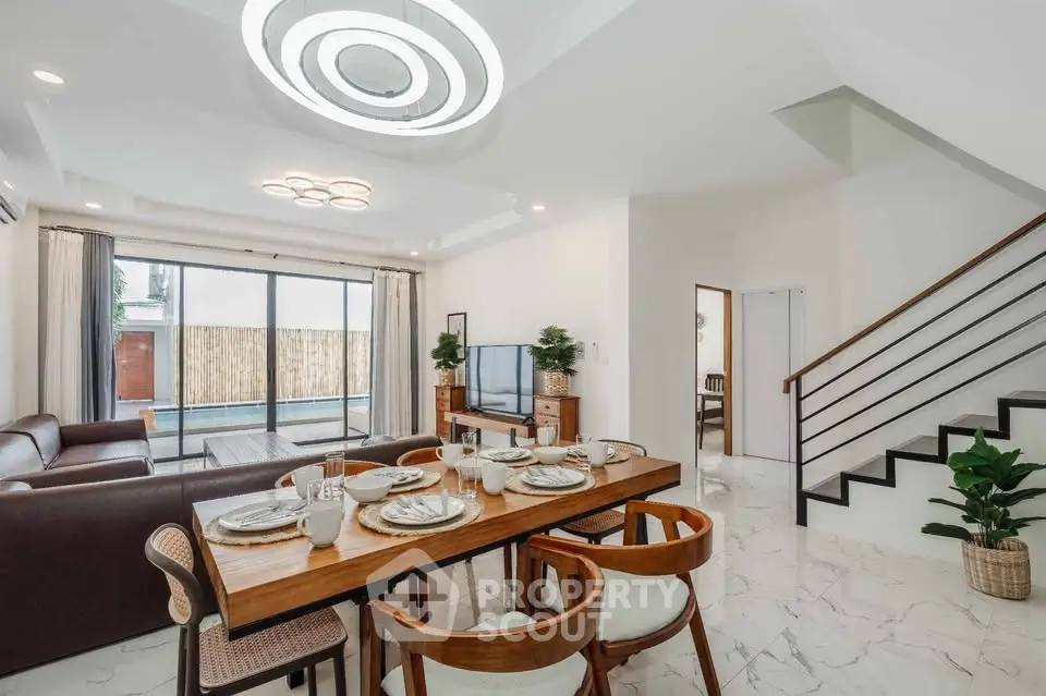 Spacious modern living room with dining area and pool view, featuring elegant decor and ample natural light.