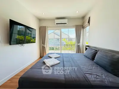 Modern bedroom with large window and wall-mounted TV, featuring a comfortable bed and natural light.