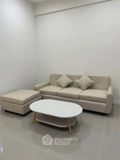 Modern living room with beige sofa and sleek coffee table on glossy tiled floor.