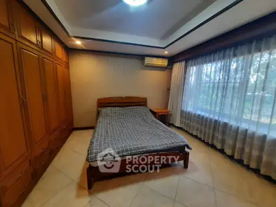 Spacious bedroom with large window and wooden wardrobe in cozy home