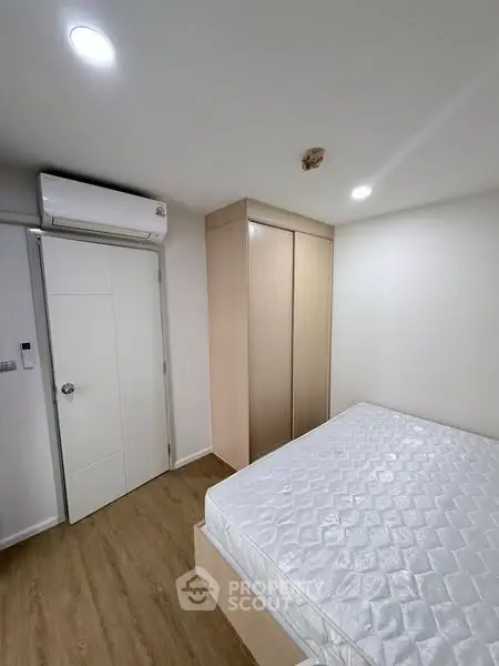 Modern minimalist bedroom with wooden flooring and built-in wardrobe