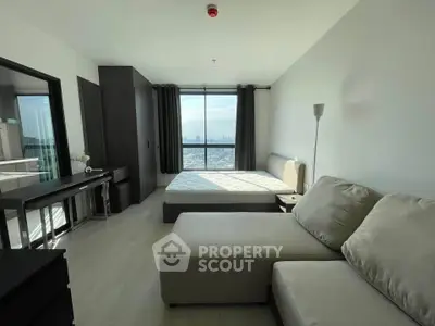 Spacious modern bedroom with city view, featuring a cozy sofa and sleek furnishings.