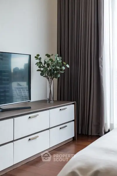 Modern bedroom with sleek TV setup and elegant curtains