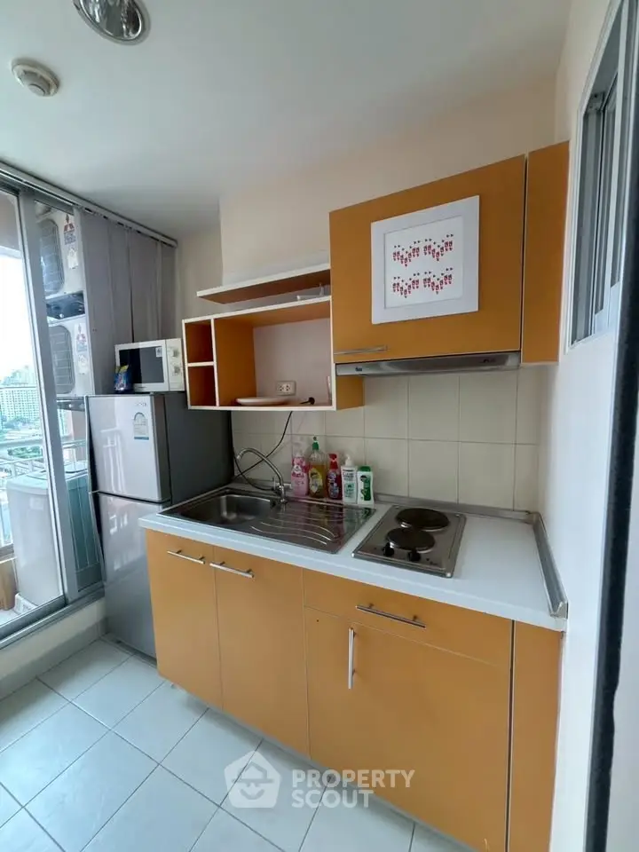 Modern kitchen with compact design and stainless steel appliances in urban apartment.