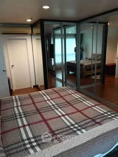 Spacious bedroom with mirrored closets and cozy decor in modern apartment