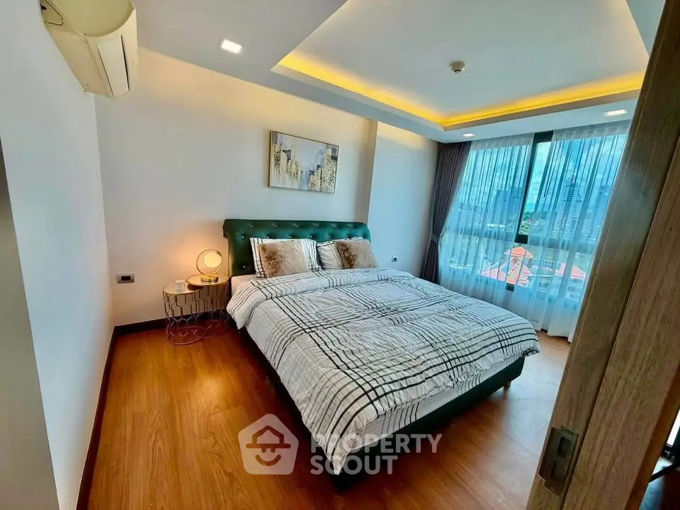 Modern bedroom with stylish decor and large window offering city views