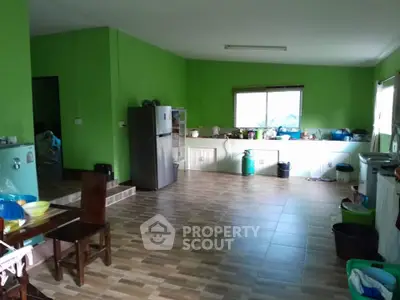 Spacious kitchen with green walls and ample natural light, featuring modern appliances and tiled flooring.