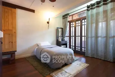 Cozy bedroom with wooden flooring and large window for natural light