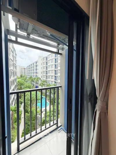 Charming balcony view overlooking lush greenery and pool in modern apartment complex.