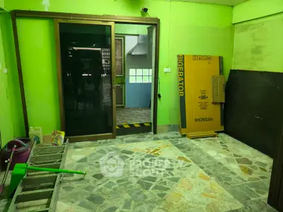 Spacious room with green walls and stone tile flooring, featuring a sliding glass door and a Hitachi refrigerator box.