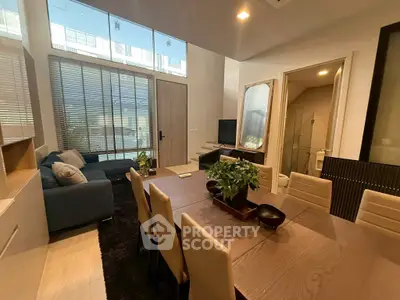 Modern living room with dining area and large windows in a stylish apartment.