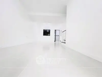 Spacious white tiled room with modern minimalist design and natural light.
