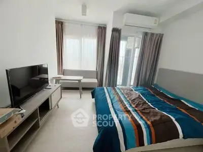 Modern bedroom with stylish decor, featuring a cozy bed, TV, and natural light from large windows.