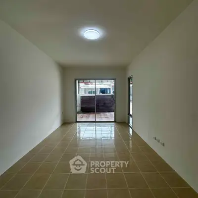 Spacious empty room with tiled floor and sliding glass doors leading to a balcony.