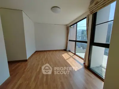 Spacious sunlit room with large windows and wooden flooring