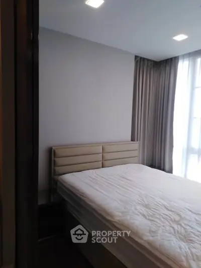 Modern bedroom with large window and elegant curtains, featuring a comfortable bed and minimalist design.