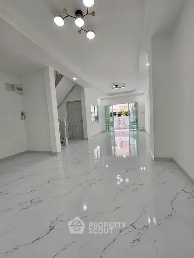 Spacious modern living room with glossy marble flooring and stylish lighting fixtures.