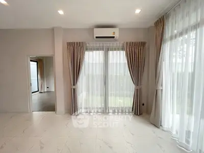 Spacious living room with large windows and elegant curtains, featuring modern air conditioning.