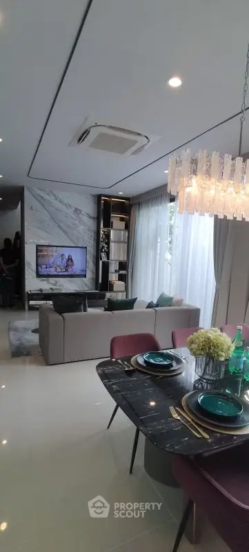 Luxurious open living and dining area with modern decor and elegant chandelier