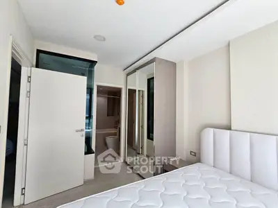 Modern bedroom with mirrored closet and ensuite bathroom in stylish apartment.