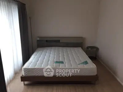 Spacious bedroom with modern bed and natural light from large window.