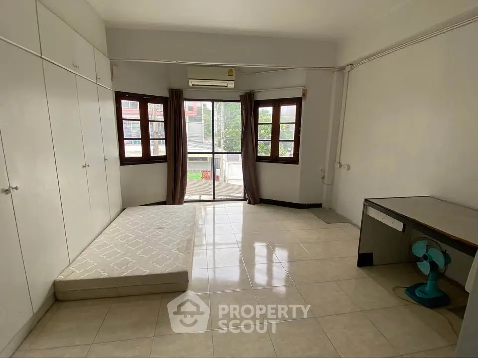 Spacious bedroom with large windows and minimalist decor, perfect for customization.