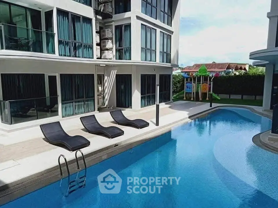 Luxurious apartment complex with modern pool and sun loungers, perfect for relaxation and leisure.