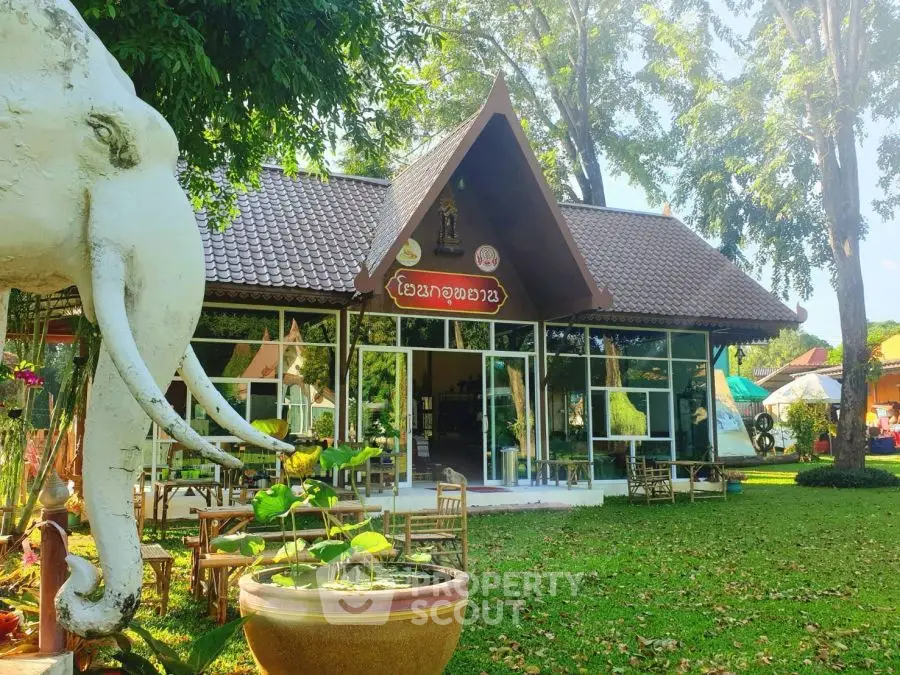 Charming traditional-style building with lush garden and elephant statue, perfect for serene living or unique business.
