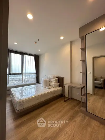 Spacious modern bedroom with large windows and wooden flooring, perfect for comfort and relaxation.