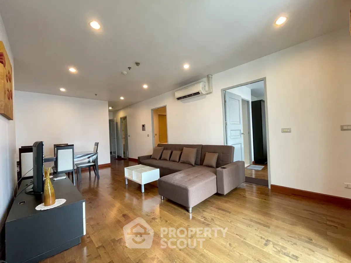 Spacious living room with modern furniture and wooden flooring in a stylish apartment.
