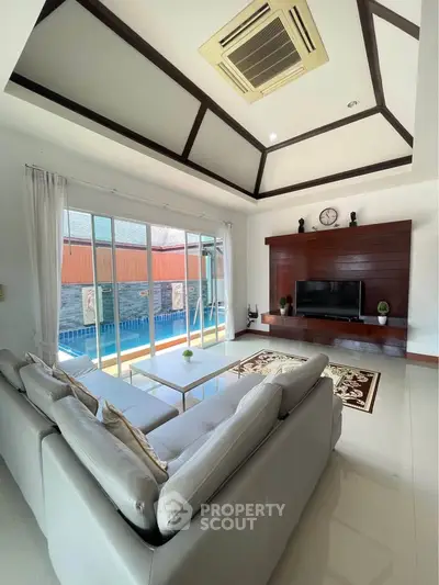 Luxurious living room with pool view, elegant decor, and high ceiling design.