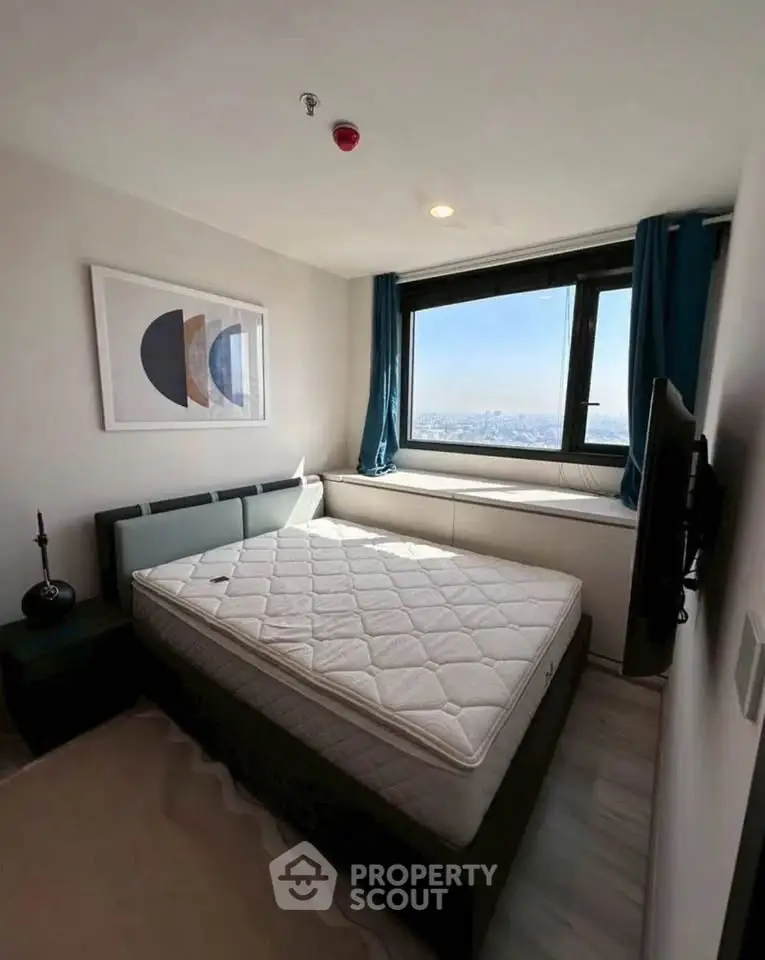 Modern bedroom with large window offering stunning city view, stylish decor, and comfortable bed.