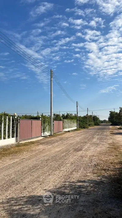 Expansive rural property with secure gated entrance and clear blue skies.