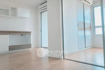 Modern minimalist apartment interior with wooden flooring and built-in storage solutions.