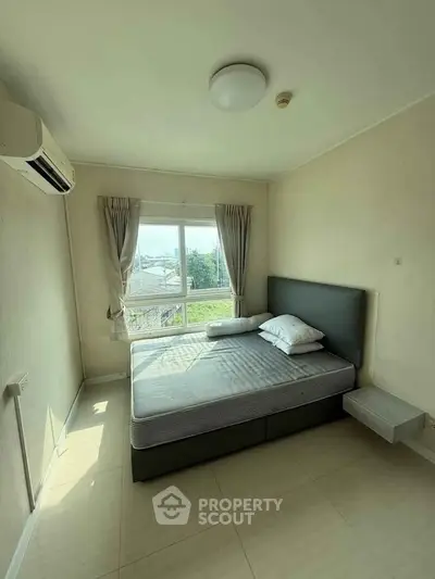 Bright bedroom with large window and modern furnishings in a cozy apartment.