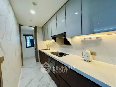 Modern kitchen with sleek cabinets and marble flooring in a stylish apartment.