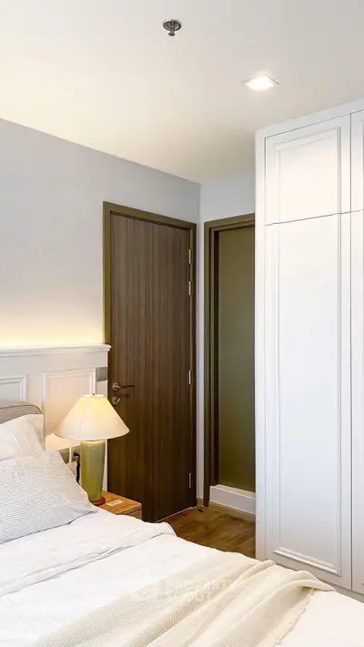 Modern bedroom with elegant decor and soft lighting, featuring a cozy bed and stylish wooden door.