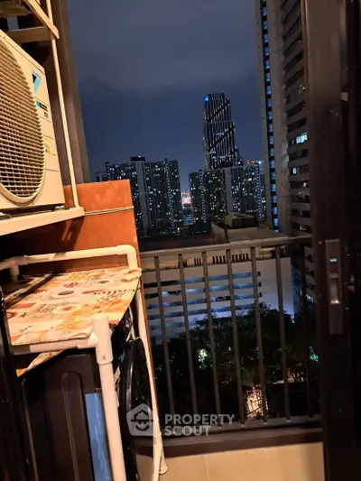 Stunning urban view from a high-rise balcony with city skyline at night, featuring modern buildings.