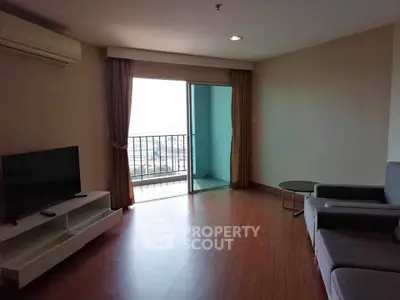 Spacious living room with balcony and modern furnishings in a high-rise apartment.